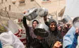 Palestinians carry empty pots during a demonstration held by the displaced Palestinians gathered in a protest carrying empty pots and pans asking for more relief aid and fuel to reach Gaza strip in Deir al-Balah, central Gaza, on Thursday, April 25, 2024.