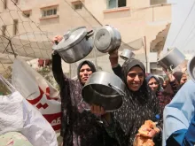 Palestinians carry empty pots during a demonstration held by the displaced Palestinians gathered in a protest carrying empty pots and pans asking for more relief aid and fuel to reach Gaza strip in Deir al-Balah, central Gaza, on Thursday, April 25, 2024.