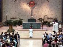 Former archbishop of Milwaukee, Wisconsin, Rembert Weakland kneels and prays as he is given a standing ovation of support after he apologized publicly for sexual indiscretions during a prayer service May 31, 2002 in St. Francis, Wisconsin. Weakland admitted to having a relationship with and paying $450,000 to former seminary student Paul Marcoux.