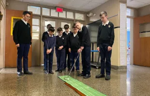 A group of third- to eighth-grade boys at St. Michael’s School in Fall River, Massachusetts, takes part in a putting competition in their after-school Young Men’s Club in 2023. Courtesy of Father Jay Mello