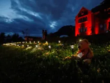 A teddy bear sits beside a lantern outside the former Kamloops Indian Residential School where flowers and cards have been left as part of a growing makeshift memorial created in response to media reports that the "remains" of 215 children have been discovered buried near the facility in Kamloops on June 5, 2021.