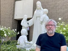 Michael Stucchi poses in front of the restored statue of Jesus with children at St. Mel's Church in Woodland Hills, California.