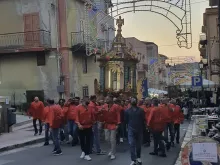 Men process with the historic cross on the feast of the Holy Cross in Montemaggiore Belsito on Sept. 14, 2022. It is considered a great honor to be one of the people to transport the heavy float in which the cross is carried.