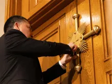 A member of the maintenance crew at the Basilica of the National Shrine of the Immaculate Conception in Washington, D.C., places a seal on the Holy Door at the basilica after Archbishop Timothy Broglio blessed the seal and doors on Dec. 3, 2023.