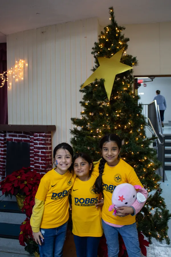 Children of Afghan immigrants to St. Louis pose in front of a Christmas tree during a holiday party on Dec. 9, 2023. Credit: Jonah McKeown/CNA