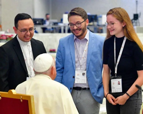 Father Ivan Montelongo, Wyatt Olivas, and Julia Oseka, all delegates representing the United States, speak with Pope Francis during a Synod on Synodality meeting in the Paul VI Hall. Credit: Vatican Media