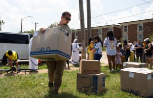 Perpetual Pilgrim Patrick Fayad lifts a heavy "Box of Mercy" filled with donations for refugee families. Credit: Jonah McKeown/CNA
