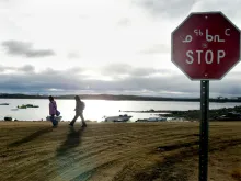 Two Inuit children return from school past a stop sign written in English in October 2002 in Iqaluit, northern Canada. Iqaluit is the capitol of Nunavut Territory in the Canadian Arctic.