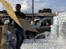 Dontavious Spann helps hand out cases of bottled water at a Mississippi Rapid Response Coalition distribution site on Aug. 31, 2022 in Jackson, Mississippi.