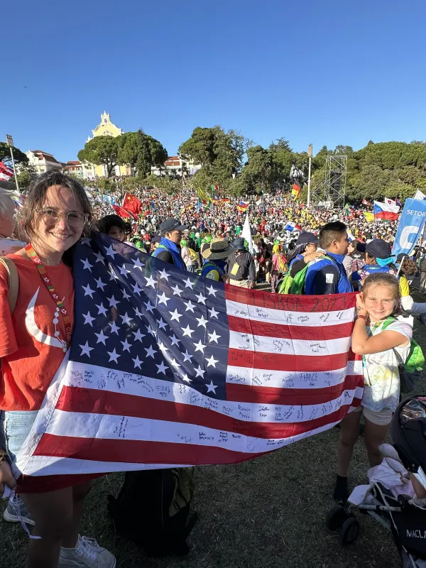 Cecilia and Catherine Love representing the United States at the Welcome Ceremony for Pope Francis at World Youth Day 2023. Photo credit: Alexis Love