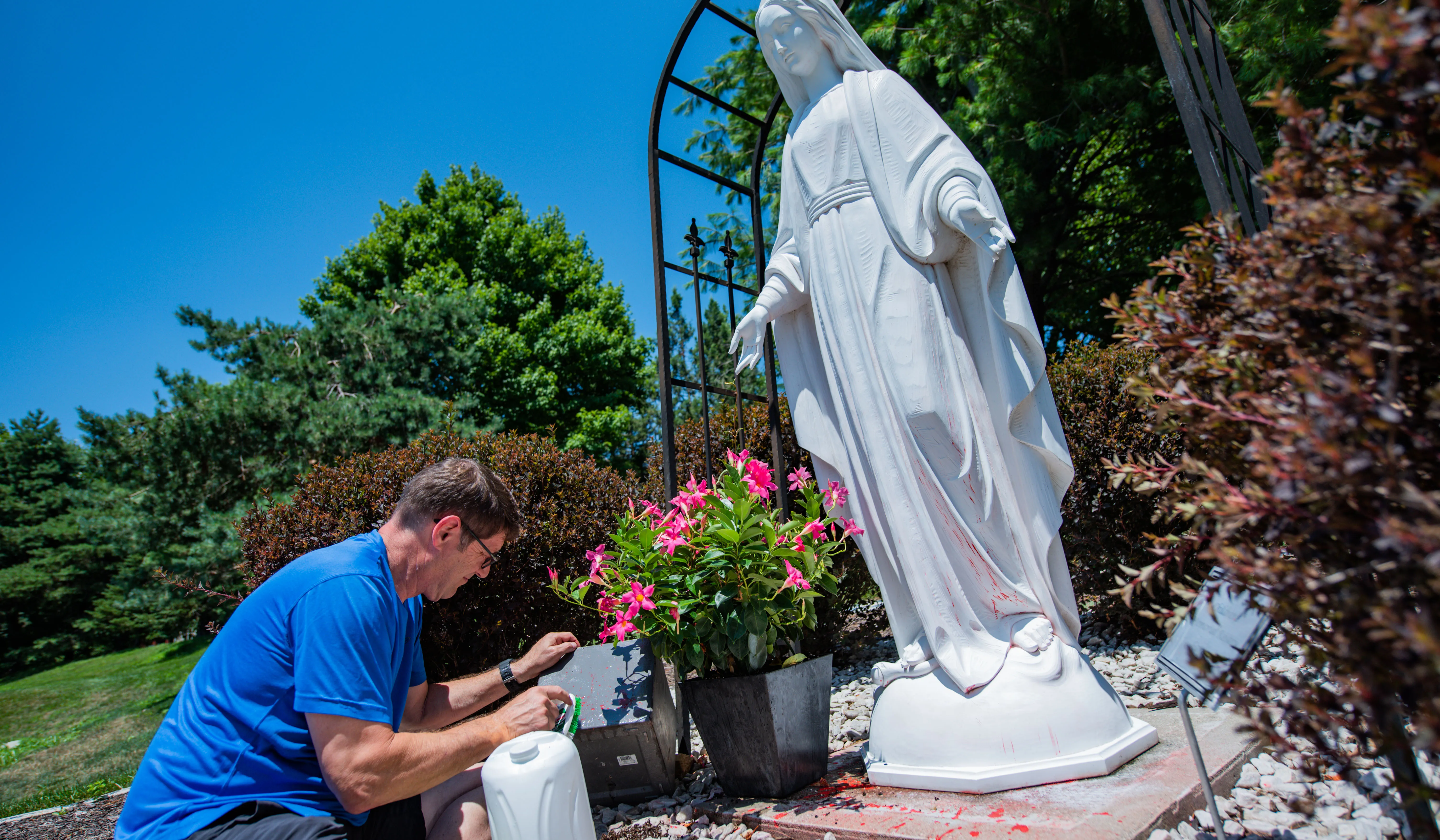 A man removes red spray paint from a statue of the Blessed Mother at the Church of the Ascension in Overland Park, Kansas.?w=200&h=150