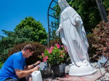 A man removes red spray paint from a statue of the Blessed Mother at the Church of the Ascension in Overland Park, Kansas.