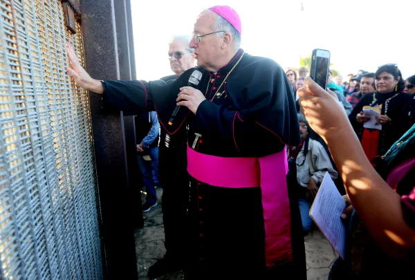 Bishop Robert W. McElroy of San Diego speaks with participants through the fence during the 23rd Posada Sin Fronteras where worshipers gather on both sides of the U.S.-Mexican border fence for a Christmas celebration, at Friendship Park and Playas de Tijuana in San Ysidro, California, on Dec. 10, 2016. Sandy Huffaker/AFP via Getty Images