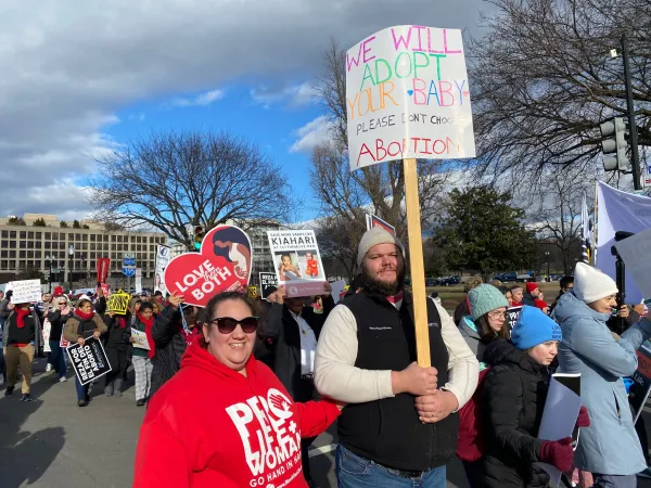 Cameron and Genevieve Mercier from Thompsontown, Pennsylvania, hold a sign that says "We will adopt your baby. Please don't choose abortion.". Katie Yoder