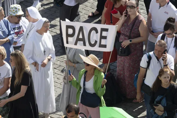 A pilgrim in St. Peter's Square for Pope Francis' weekly Angelus address on Oct. 8, 2023, holds a sign with the word "pace," Italian for "peace." Credit: Vatican Media