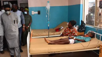 State officials walk past injured victims on hospital beds being treated for wounds following an attack by gunmen at St. Francis Xavier Catholic Church in Owo, southwest Nigeria, on June 5, 2022.