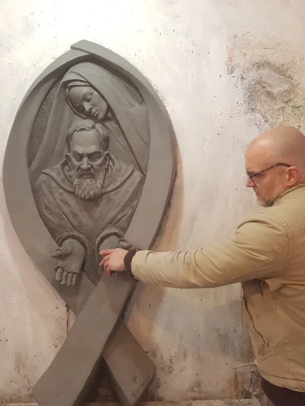 Artist Timothy P. Schmalz touches the hands of Padre Pio in his sculpture that includes the Blessed Virgin Mary. Courtesy of Timothy P. Schmalz