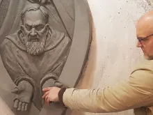 Artist Timothy P. Schmalz touches the hands of Padre Pio in one of his sculptures.