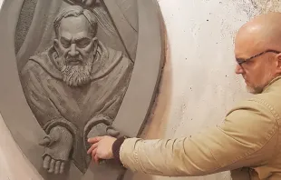 Artist Timothy P. Schmalz touches the hands of Padre Pio in one of his sculptures. Courtesy of Timothy P. Schmalz