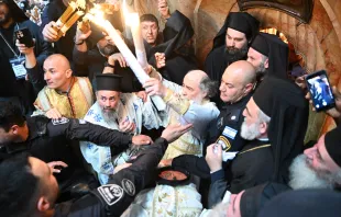 The Greek Orthodox Patriarch Theophilos III exits the Aedicule of the Holy Sepulcher on May 4, 2024, in Jerusalem, showing the faithful the two candles just lit from the oil lamp that is believed to have been miraculously ignited inside Jesus' tomb. Credit: Studio Sami Jerusalem