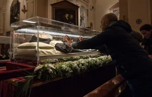 A man places his hands on the glass urn holding the remains of St. Pio in Pietrelcina, Italy, in 2016. St. Pio was found to be in a state of partial deterioration and partial preservation when his coffin was opened in 2008, but experts present at the exhumation have said there was no supernatural quality to what was preserved. Artificial preservation techniques have since been applied to conserve his body from further deterioration and a lifelike mask has been placed over his skull. Ivan Romano/Getty