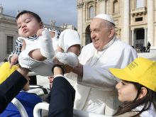Pope Francis receives a baby for a blessing as pilgrims gather in St. Peter’s Square for the pope’s general audience on Wednesday, April 10, 2024.