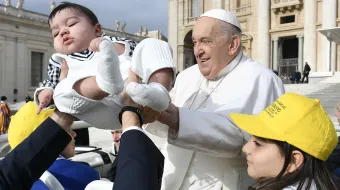 Pope Francis receives a baby for a blessing as pilgrims gather in St. Peter’s Square for the pope’s general audience on Wednesday, April 10, 2024.