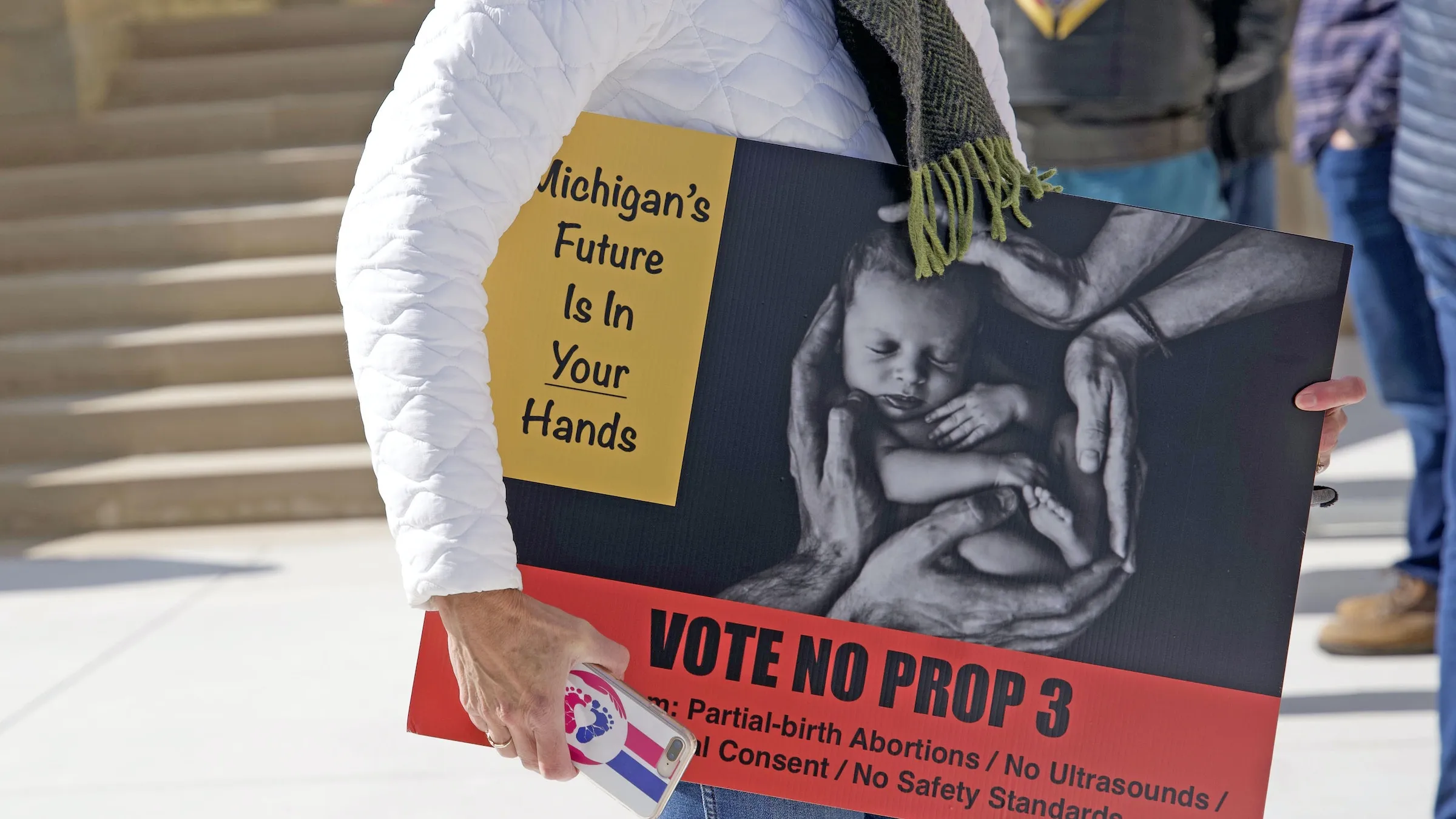 A woman carries a sign warning of the dangers of Proposal 3, the so-called "Reproductive Freedom for All" constitutional amendment, during an Oct. 15 rally at the state capitol building in Lansing. If the controversial proposal passes, it would mean the end of all abortion-related regulation in Michigan, including for children and minors.?w=200&h=150