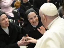 Pope Francis smiles with two religious sisters during his general audience on Jan. 11, 2023