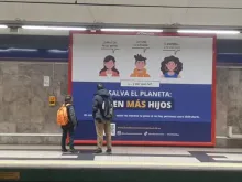 A father and son observe pro-natalist billboard campaign in Madrid, Spain.