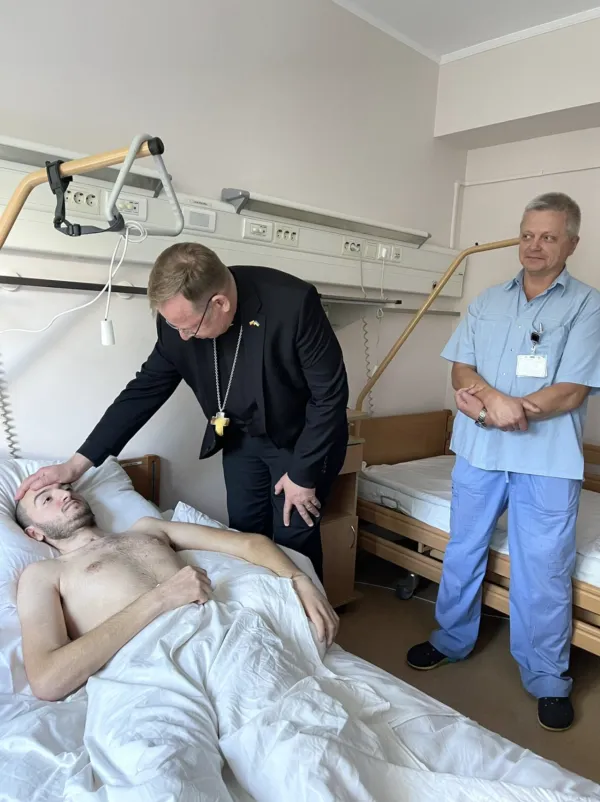 Archbishop Gintaras Grušas with an injured Ukrainian soldier. Photo courtesy of Father Andriy Zelensky.
