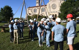 A group of volunteers stand in front of a Notre-Dame Cathedral truss replica at the Catholic University of America in Washington, D.C., on Sept. 26, 2022. Patrick G. Ryan