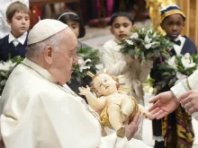 Pope Francis takes a figure of the Christ child in his arms at the end of the Vatican's Mass for the Nativity of the Lord on Dec. 24, 2023.