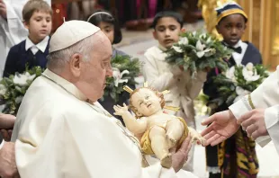 Pope Francis takes a figure of the Christ child in his arms at the end of the Vatican's Mass for the Nativity of the Lord on Dec. 24, 2023. Vatican Media