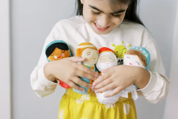 A little girl holds several of the plush saint Shining Light Dolls. Credit: Shining Light Dolls