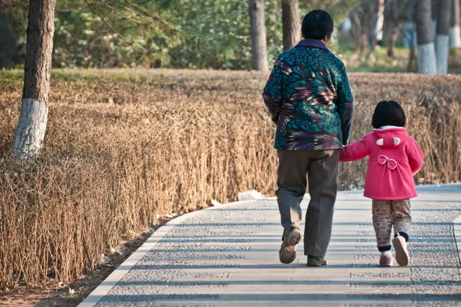 An elderly Chinese woman walks with her granddaughter.
