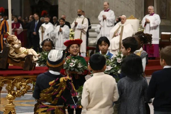 Children place flowers before a figure of the Christ child enthroned in front of the altar of St. Peter's Basilica. Credit: Vatican Media