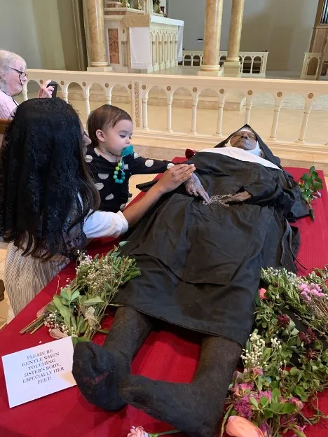 Tanya Schultz and her daughter pray at the body of Sister Wilhelmina Lancaster on May 20, 2023. Credit: Photo courtesy of Joe and Tanya Schultz