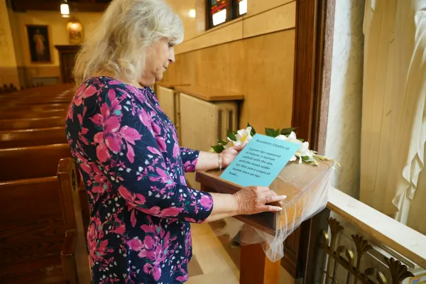 Susan Kraus, a sacristan at St. Hyacinth Parish reads a description of Mary from Revelation 12, describing the Blessed Mother as standing on the moon, wearing a crown with 12 stars. May 2024. Credit: Daniel Meloy | Detroit Catholic