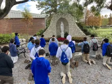A group of students from Jesuit High School, an all-boys school in Tampa, Florida, praying in front of a statue of Our Lady.