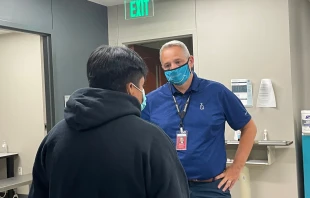 Antonio Fernandez, CEO of Catholic Charities San Antonio, aids a migrant following the death of dozens of people abandoned in a truck. Tara Ford