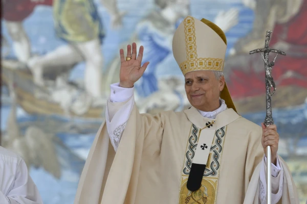 Pope Leo XIV waves during the inaugural Mass of his pontificate, held in St. Peter's Square on May 18, 2025. He stands in front of a Flemish tapestry depicting the dialogue between Jesus and Peter after the miraculous catch of fish. Credit: Vatican Media