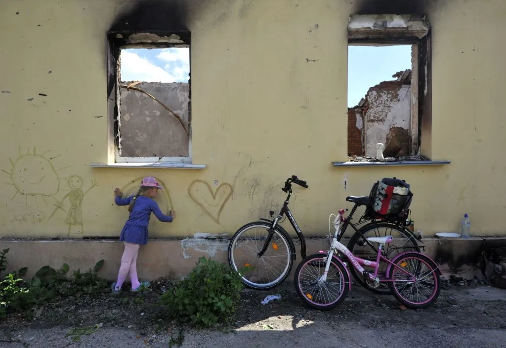 A young girl draws on the wall of a destroyed house in the village of Andriivka, Kyiv region, on June 3, 2022 on the 100th day of the Russian invasion of Ukraine. Sergei Chuzavkov/AFP via Getty Images)?w=200&h=150