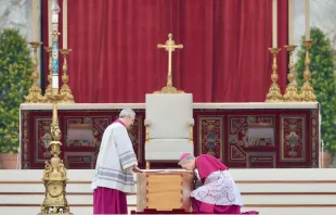 Archbishop Georg Gänswein (right), the longtime personal secretary for Benedict XVI,  kneels to kiss the book of the Gospels atop the coffin of the pope emeritus on Jan. 5, 2023, in St. Peter's Square Daniel Ibañez/CNA