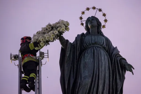 A firefighter places a wreath of flowers on the statue of the Virgin Mary’s outstretched arm. Credit: Daniel Ibanez/CNA