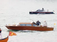 Pope Francis waves while traveling by boat in Venice, Italy, for a meeting with young people at the Basilica della Madonna della Salute on April 28, 2024. Earlier in the day he met with inmates at a women's prison.