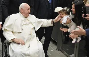 Pope Francis, seated in a wheelchair, greets a child during the pope's general audience at the Vatican on Jan. 25, 2023. Vatican Media