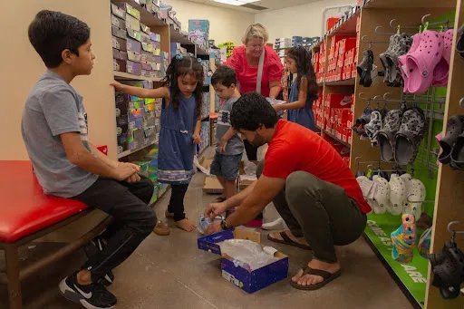 Ann Wittman helps the Wardak children, and father Farid, shop for shoes at a store in Kirkwood, Missouri, near St. Louis. Jonah McKeown/CNA